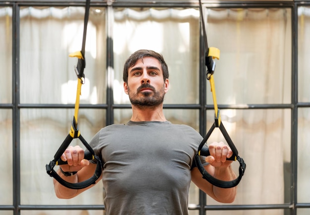 Homme fort faisant de l'exercice avec des bandes TRX