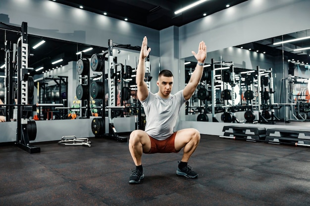 Un homme fort fait des squats et des exercices de fitness dans une salle de sport