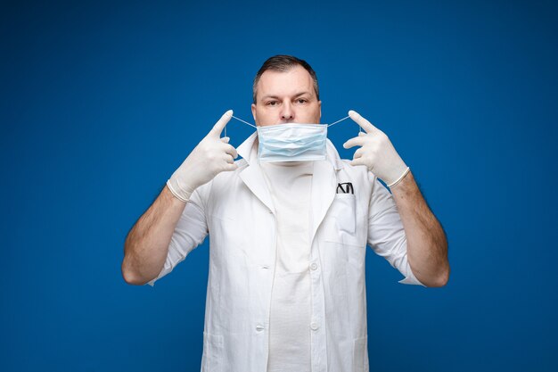 Un homme fort avec des lunettes, une blouse médicale blanche et un masque