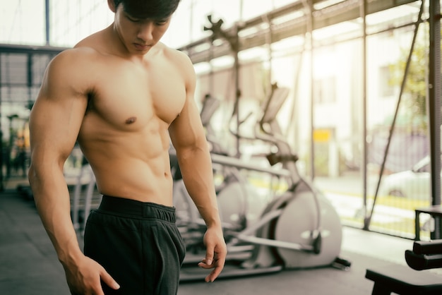 homme fort de remise en forme posant un corps musclé et faire des exercices pour bodybuilder dans la salle de gym