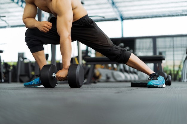 homme fort de remise en forme posant un corps musclé et faire des exercices pour bodybuilder dans la salle de gym