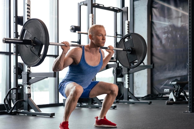 Un homme fort et sportif soulevant une barre au gymnase.