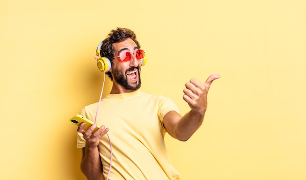 Homme fou expressif se sentant fier, souriant positivement avec les pouces vers le haut avec des écouteurs