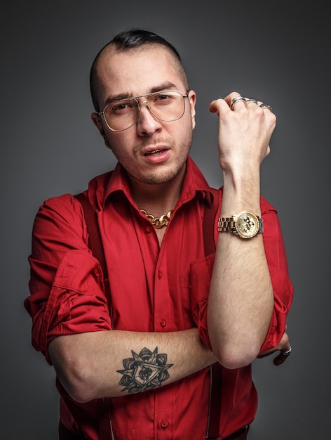 Homme fou en lunettes de t-shirt rouge et tatouage sur les mains isolés sur gris.