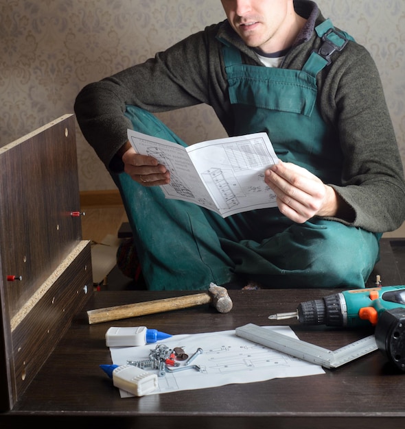 Homme frustré lisant les instructions et assemblant des meubles à monter soi-même bricolage nouvelle maison et concept de déménagement