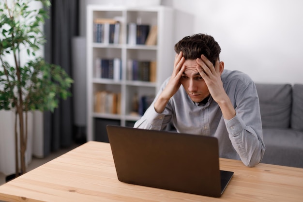 Homme frustré regardant sur un ordinateur portable