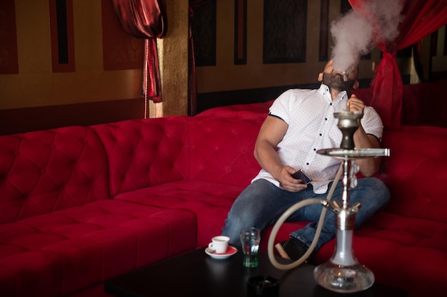 Homme fumant la chicha dans le café arabe