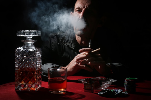 L'homme fume la pipe et joue au poker