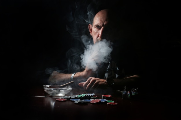 L'homme fume la pipe et joue au poker