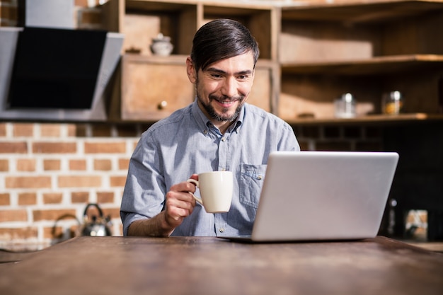 Homme gai, boire du café en lisant les actualités en ligne