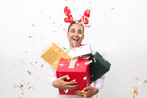 Homme gai avec des boîtes-cadeaux et des confettis autour