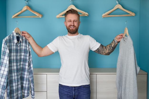 Homme gai choisissant des vêtements près de la garde-robe