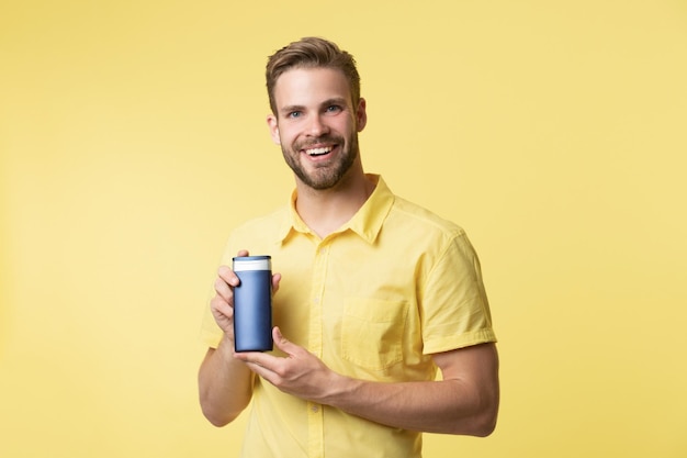 Homme gai avec des cosmétiques après-rasage isolé sur homme jaune avec des cosmétiques après-rasage