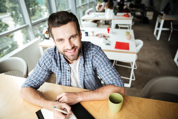 Homme gai dans le coworking de bureau tout en écrivant des notes