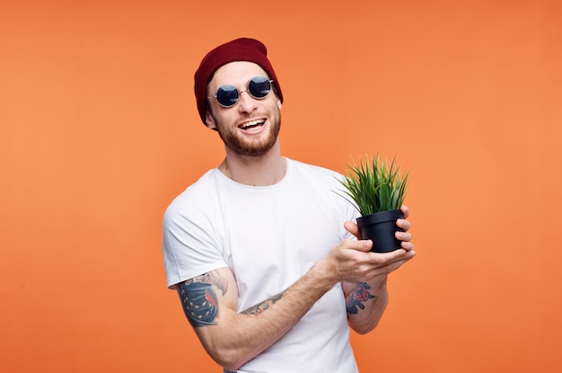 Homme gai dans des lunettes de soleil tenant un fond orange de fleur