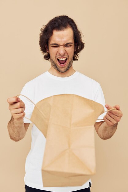 Homme gai dans un t-shirt blanc avec un style de vie de sac en papier inchangé