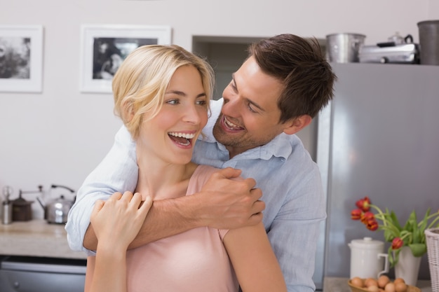Homme gai embrassant la femme par derrière dans la cuisine