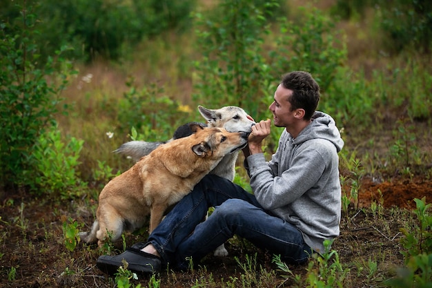 Homme gai jouant avec des chiens sur le pré