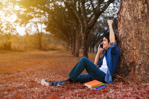 homme gai, parler sur téléphone mobile avec la main levée dans le parc