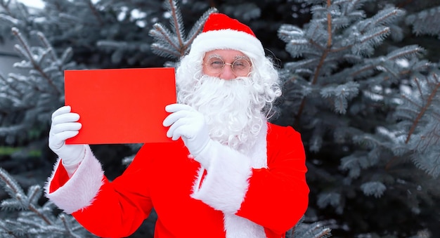 Homme gai le père Noël dans un costume de Noël tenant un signe vierge rouge de l'espace de copie