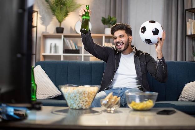 Homme gai regardant un match de football à la télévision à la maison