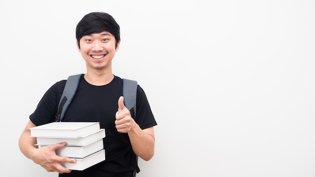 Homme gai avec sac à dos d'école et tenant des livres pouce vers le haut sourire heureux visage copie espace