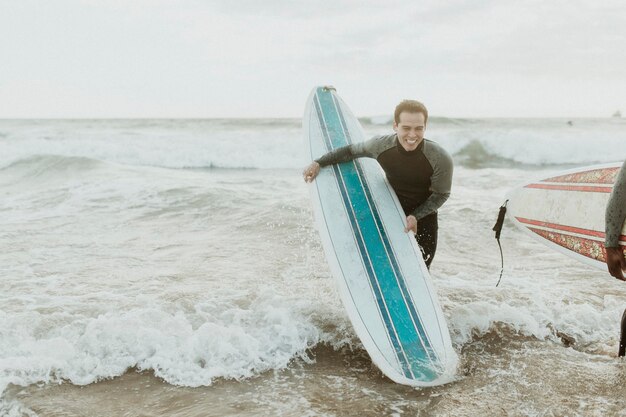 Homme gai surfant à la plage