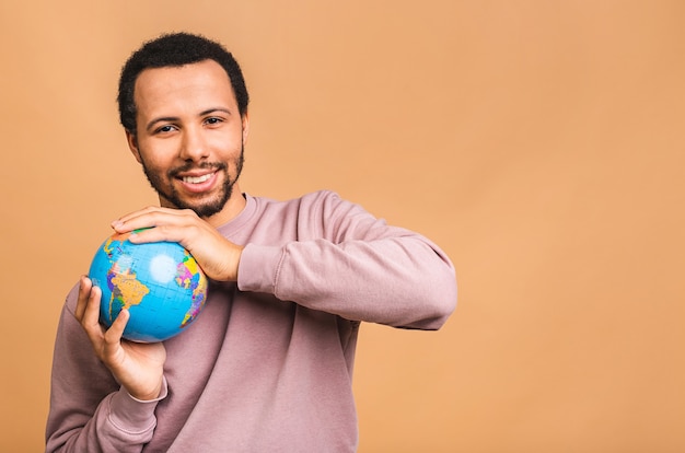 Homme gai tenant le globe avec amour et soin isolé sur beige