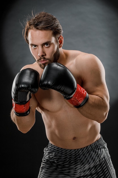 Un homme en gants de boxe Un homme boxe sur fond noir Le concept d'un mode de vie sain