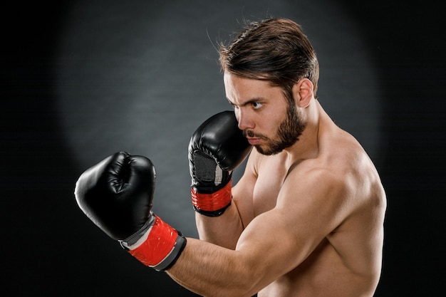 Un homme en gants de boxe Un homme boxe sur fond noir Le concept d'un mode de vie sain