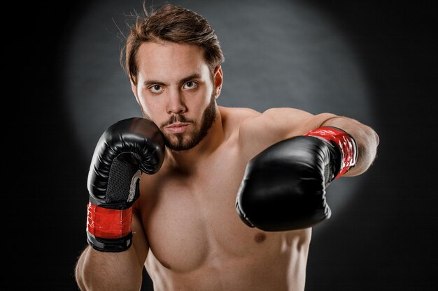 Un homme en gants de boxe Un homme boxe sur fond noir Le concept d'un mode de vie sain