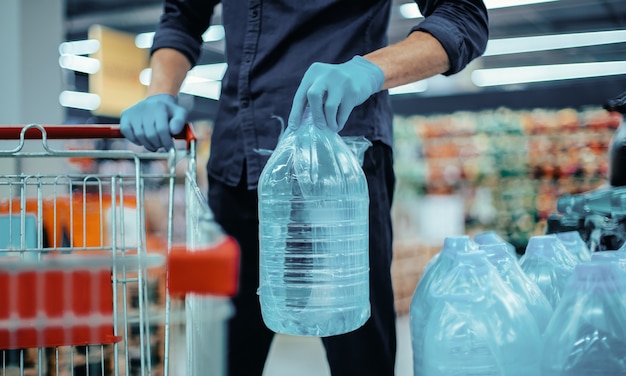 Homme en gants de protection avec une bouteille d'eau potable