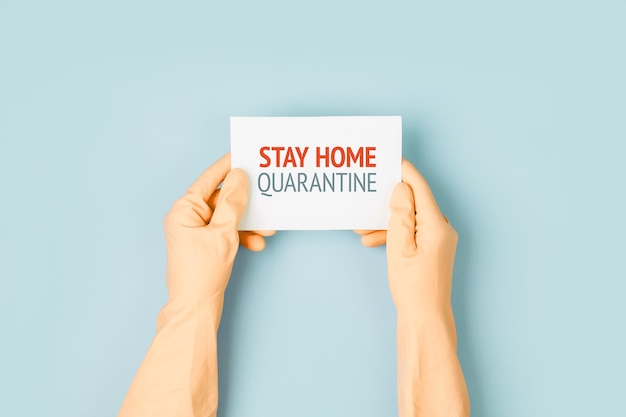 L'homme en gants de protection tient une affiche d'avertissement. L'épidémie de coronavirus covind-19 2019-ncov. Quarantaine, rester à la maison, travailler à domicile.