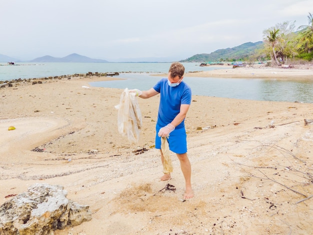 Un homme en gants ramasse des sacs en plastique qui polluent la mer