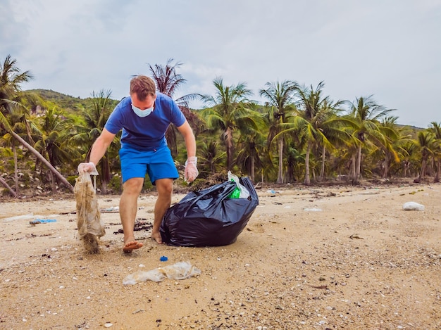 Un homme en gants ramasse des sacs en plastique qui polluent la mer