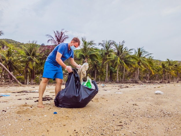 Un homme en gants ramasse des sacs en plastique qui polluent la mer