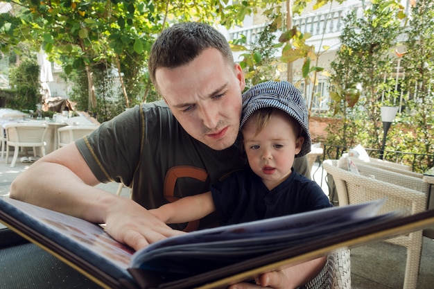 Homme avec garçon explorant un livre sur la terrasse