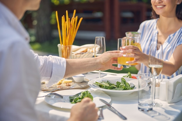 homme gardant le verre avec de la limonade orange à la main à la table à manger