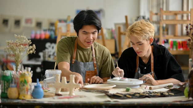 Un homme gay aime peindre une assiette en céramique dans un atelier d'artisanat créatif avec son petit ami