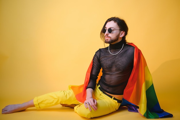 Un homme gay tient un drapeau rayé arc-en-ciel isolé sur fond coloré portrait en studio Mode de vie des gens concept lgbtq