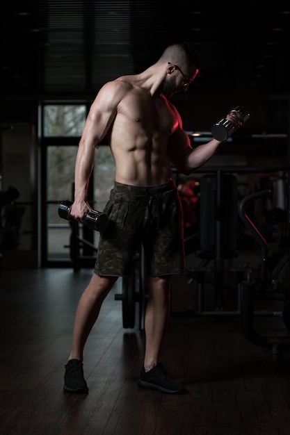 Homme geek avec haltère exerçant des biceps