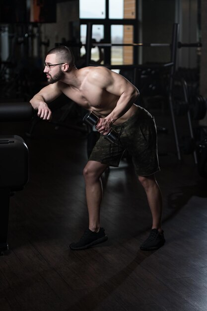 Homme geek avec haltère exerçant des triceps