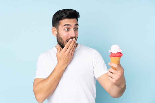 homme avec une glace au cornet sur bleu avec surprise et expression faciale choquée