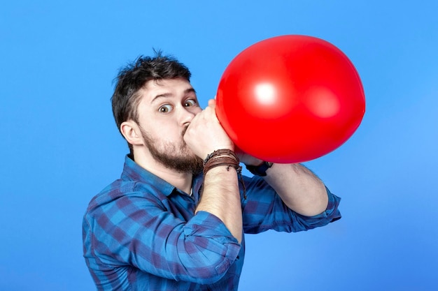 Homme gonflant un ballon rouge