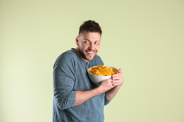 Homme gourmand cachant un bol avec des frites sur fond clair