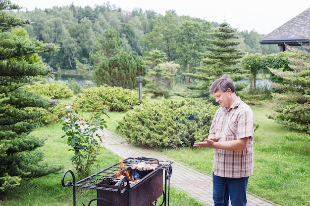 L'homme grille dans le jardin en été