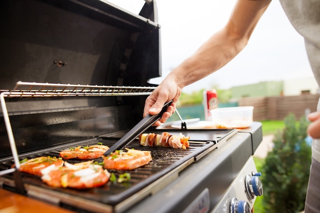 Homme griller la viande et les légumes sur un grill