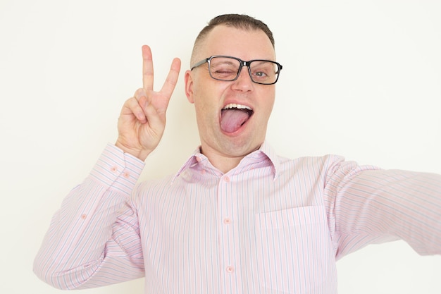 Homme grimaçant drôle à lunettes prenant selfie.