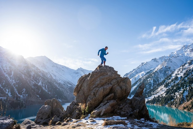 Homme grimpant sur un énorme rocher sur un point de vue sur un lac de montagne