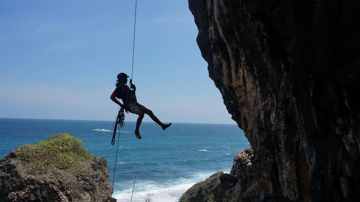Photo l'homme grimpe sur la montagne contre la mer